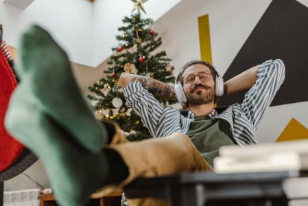 Un hombre escucha música navideña, relajado en el sofá
