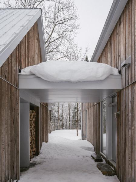 Un ligero conector techado une los dos volúmenes, creando un espacio de almacenamiento resguardado y entradas protegidas que unifican el conjunto