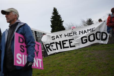 People hold up a banner for Renee Good, who was shot and killed by an Immigration and Customs Enforcement agent in Minneapolis, at a protest and rally against immigration enforcement Sunday, Jan. 11, 2026, in Seattle. (AP Photo/Lindsey Wasson)