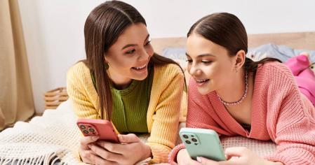 Dos adolescentes compartiendo tiempo usando su móvil
