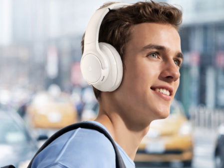 Joven usando auriculares inalámbricos de diadema mientras camina por la ciudad