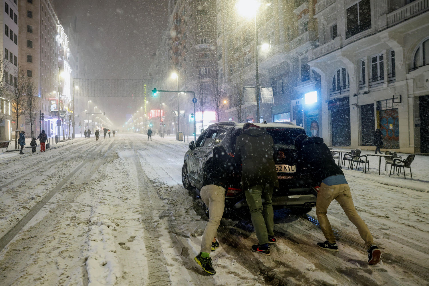 Varias personas empujan un coche en la Gran Vía, en Madrid, en una jornada en la que la Agencia Estatal de Meteorología (Aemet) ha activado el nivel rojo por la previsión de fuertes nevadas en varias zonas de las Comunidad de Madrid, entre ellas su capital