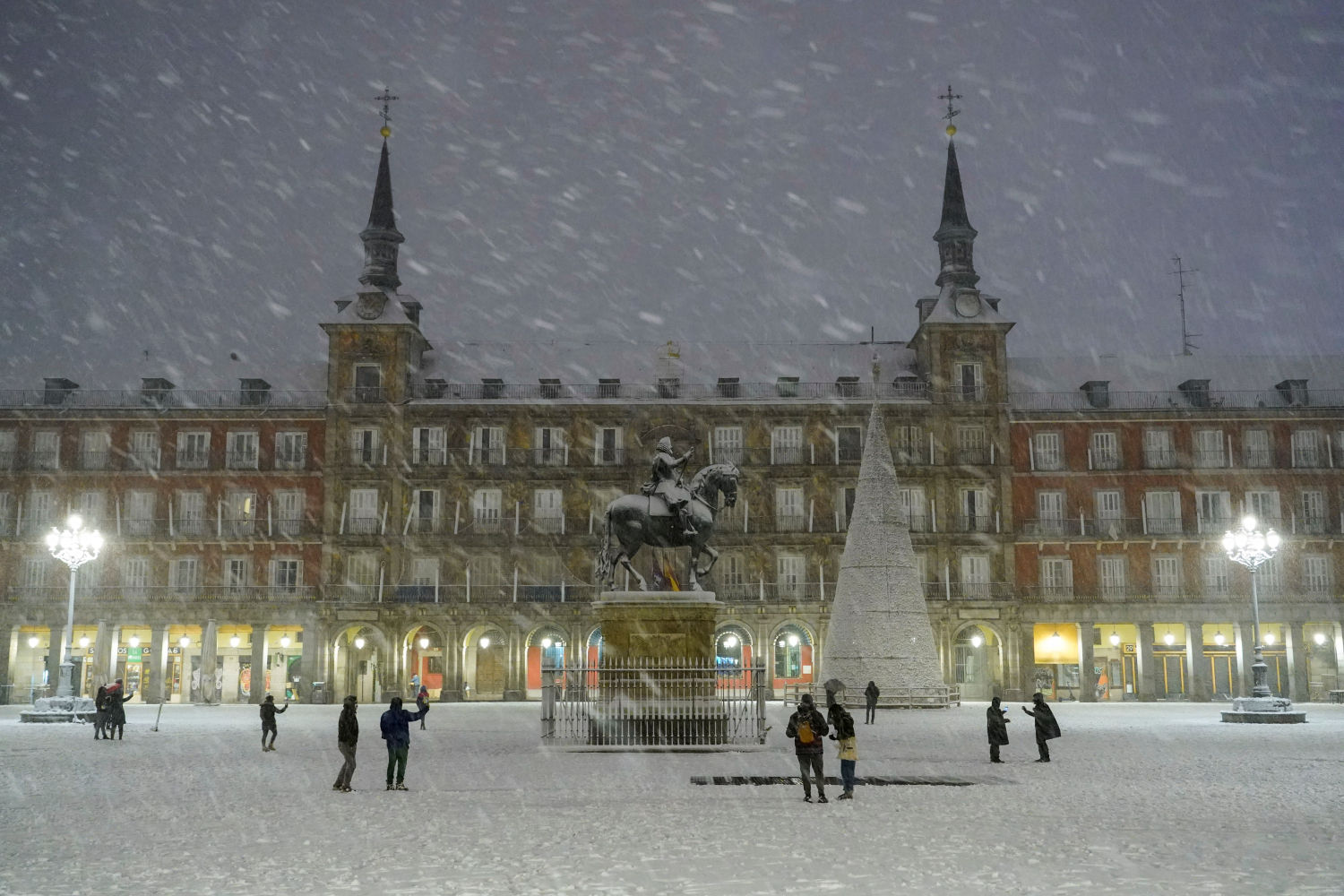 People stand at Plaza Mayor square during snowfall in Madrid, Spain, January 8, 2021. REUTERS/Juan Medina
