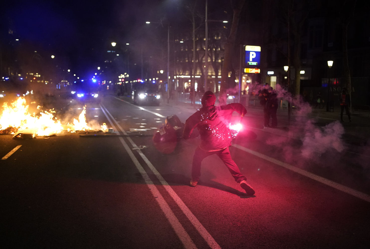 A demonstrator throws a flare at police during clashes after a protest condemning the arrest of rap singer Pablo HasÃ©l in Barcelona, Spain, Tuesday, Feb. 16, 2021. Violent street protests have erupted in some Spanish cities after police arrested a rapper who resisted imprisonment and has portrayed his case as a fight for free speech. (AP Photo/Joan Mateu)