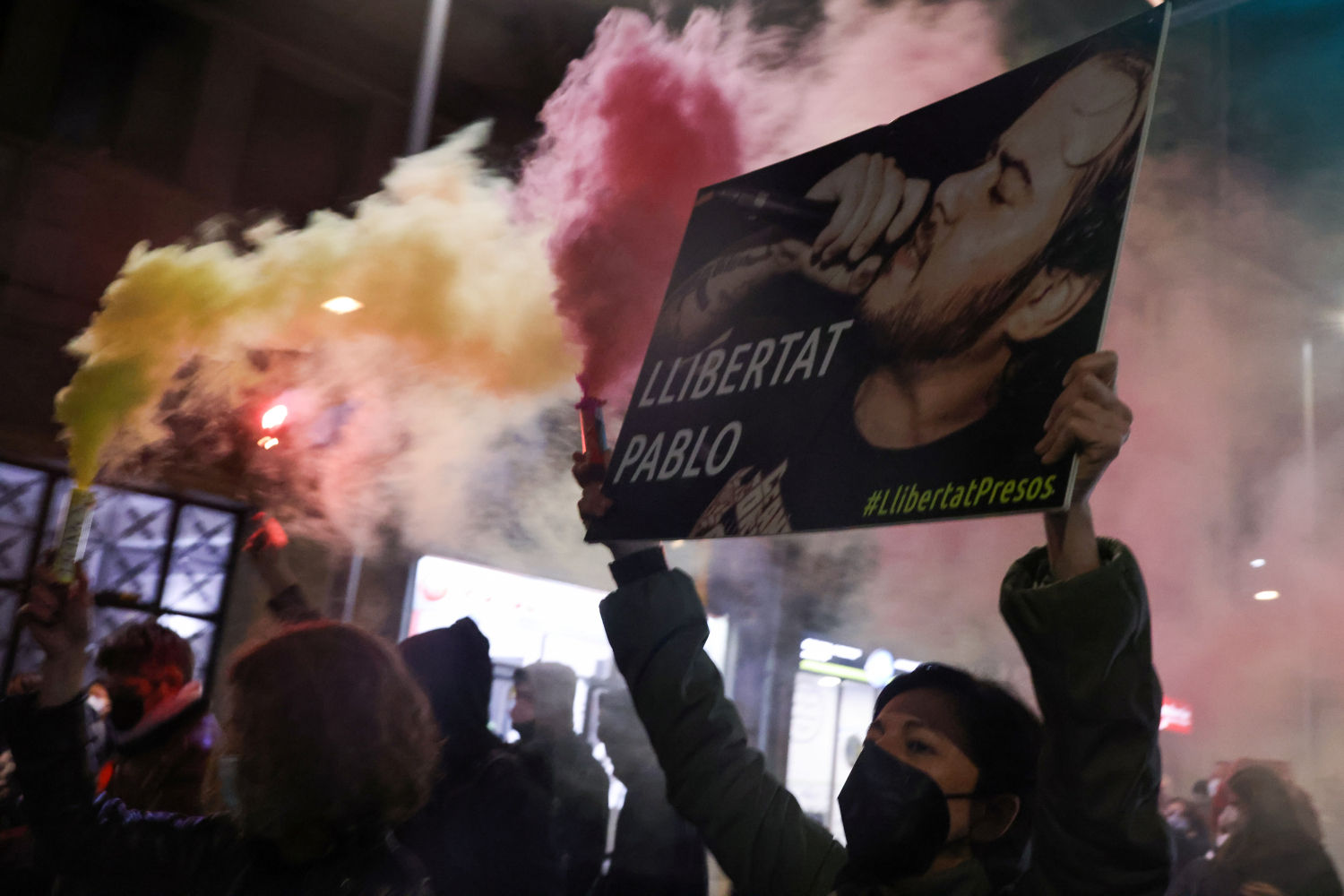 A supporter of Catalan rap singer Pablo Hasel holds a sign during a protest against his arrest, after he was given a jail sentence on charges of glorifying terrorism and insulting royalty in his songs, in Barcelona, Spain, February 16, 2021. The sign reads 