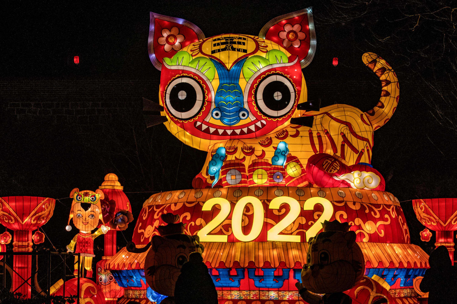 Varias personas contemplan una exhibición de coloridas luces antes del año nuevo 2022 en Yantai, en la provincia oriental de Shandong, China.