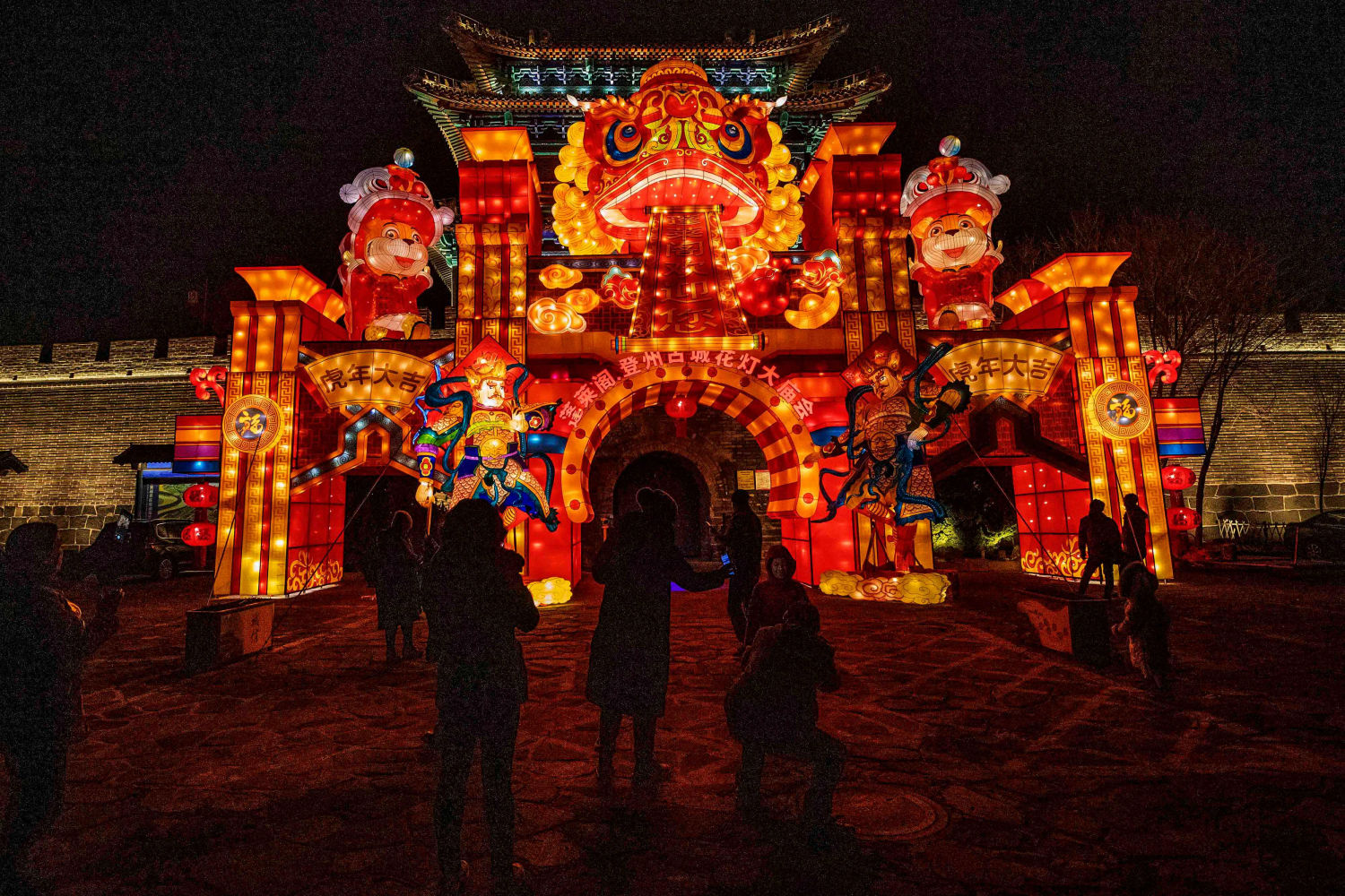 Varias personas contemplan una exhibición de coloridas luces antes del año nuevo 2022 en Yantai, en la provincia oriental de Shandong, China.