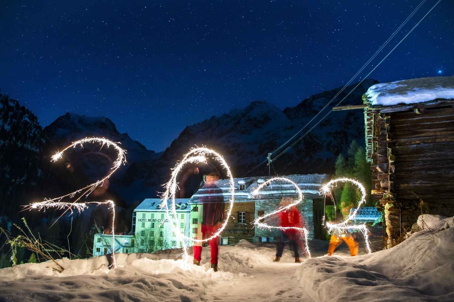 Una foto de larga exposición muestra a personas 'pintando' con luz un 2022 para dar la bienvenida al Año Nuevo, con las montañas suizas al fondo, en Arolla, Suiza.