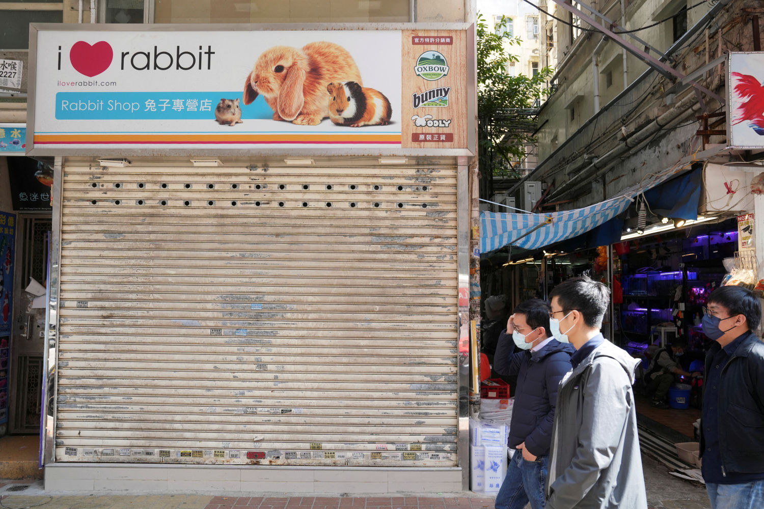 Los peatones pasan frente una tienda de mascotas cerrada en el distrito de Mong Kok (Hong Kong) después de que se ordenara sacrificar los hámsteres para frenar el brote de la enfermedad coronavirus.