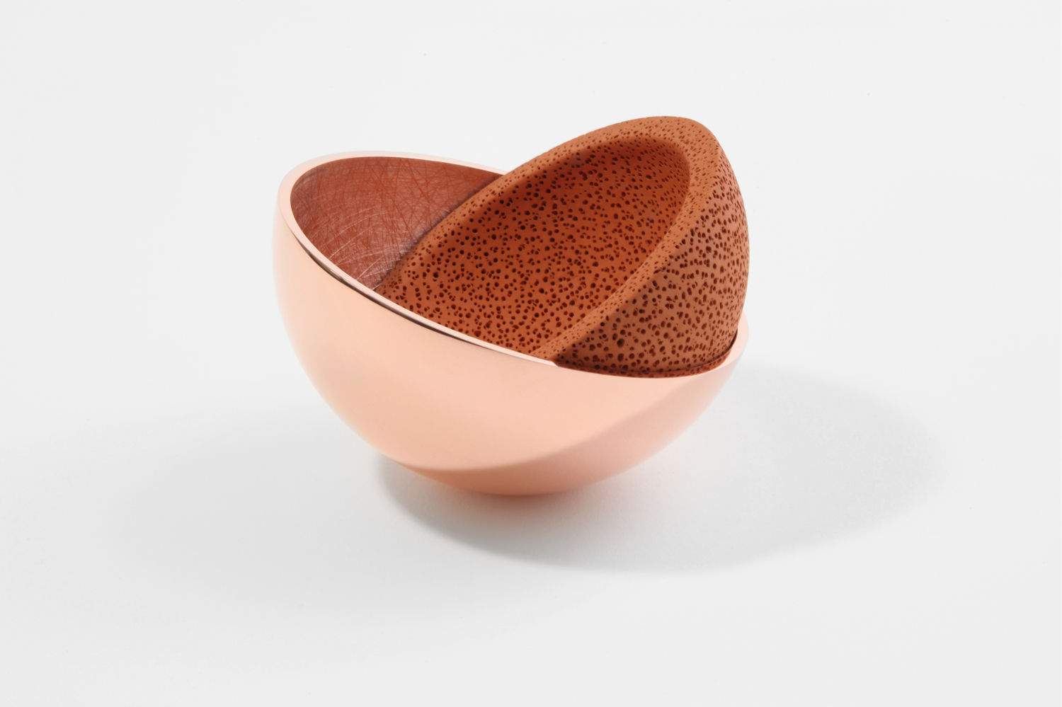 Polarity & Unity  de Ingrid Rügemer. En I·lacions Design Gallery. Objeto formado por dos recipientes ensamblables. Uno de cobre pulido, refleja la luz , el otro de terracota roja perforada es mate