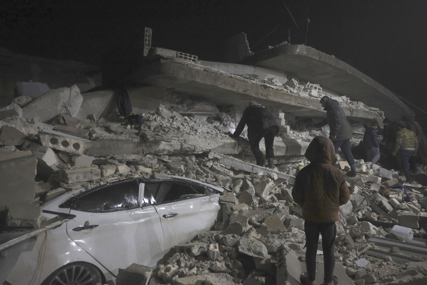 Ciudadanos sirios buscan entre los escombros de un edificio derruido por el terremoto en el pueblo de Azmarin, en Idlib
