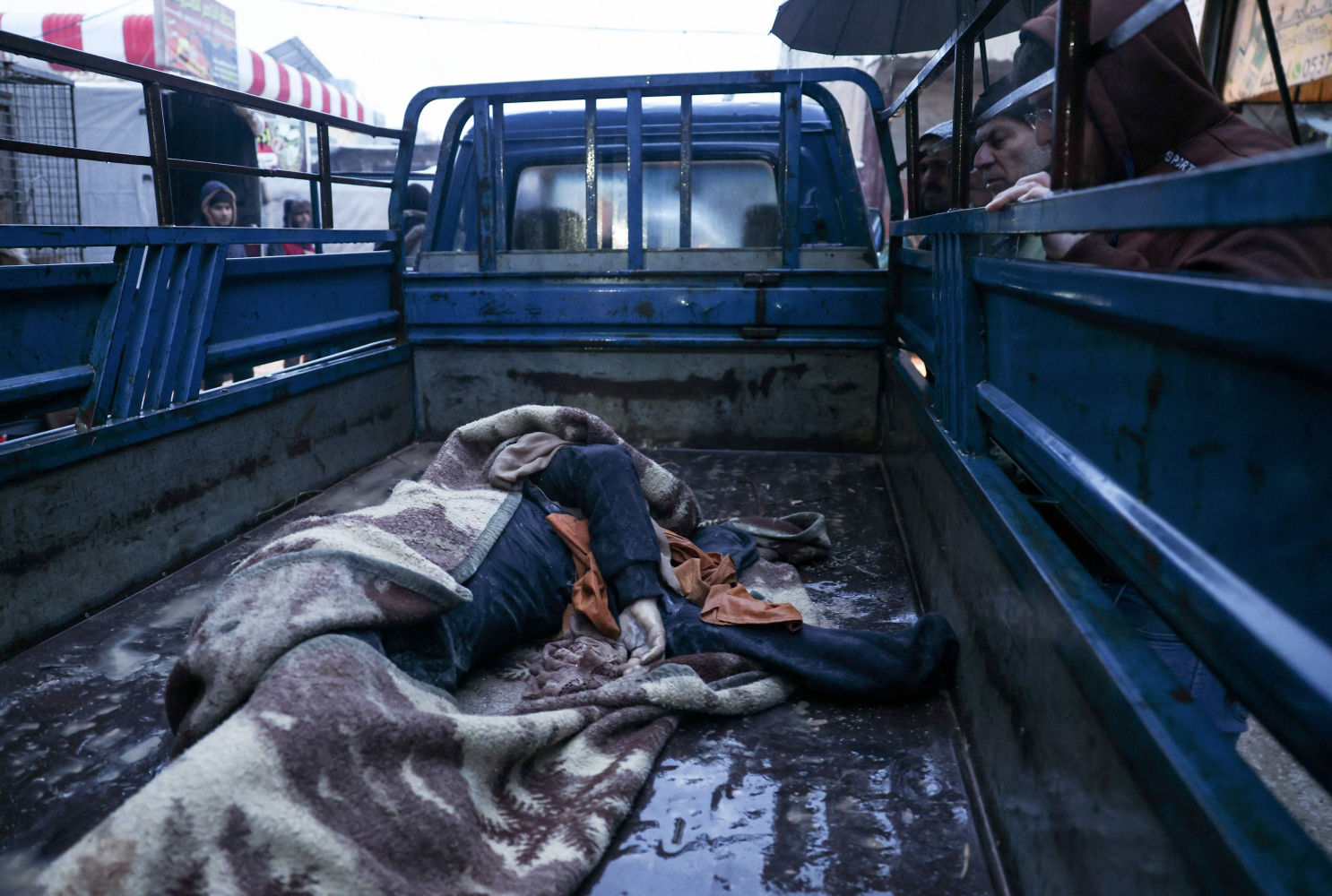 La gente observa el cadáver de una víctima que murió en el terremoto en Azmarin, cerca de la frontera turca, en Siria