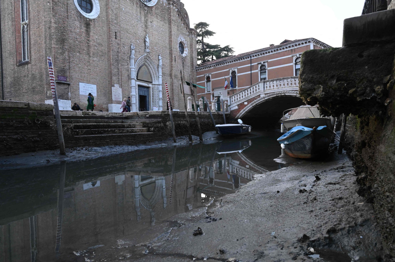 Esta fotografía tomada el 20 de febrero de 2023 muestra una góndola amarrada en el Canal Grande de Venecia, durante una fuerte marea baja en la ciudad laguna de Venecia