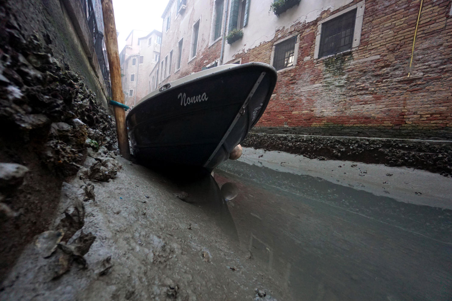 Un pequeño bote se encuentra en el fondo de un canal interno durante la marea baja en Venecia, Italia, el 17 de febrero de 2023