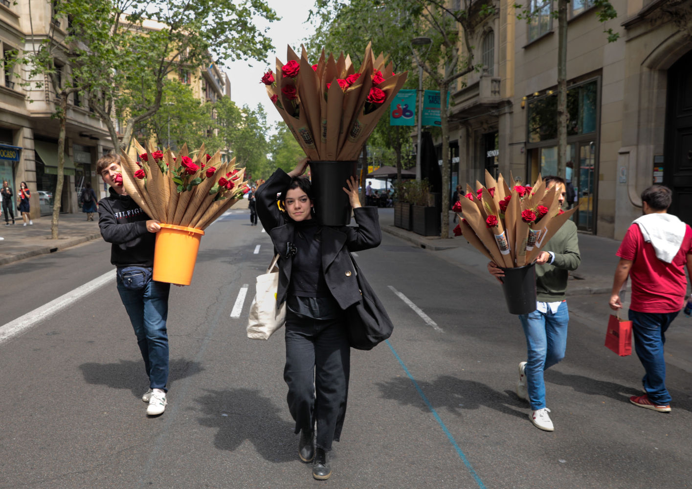 Tres jóvenes portando cubos llenos de rosas en un tramo de la calle Mallorca de Barcelonacortada al tráfico