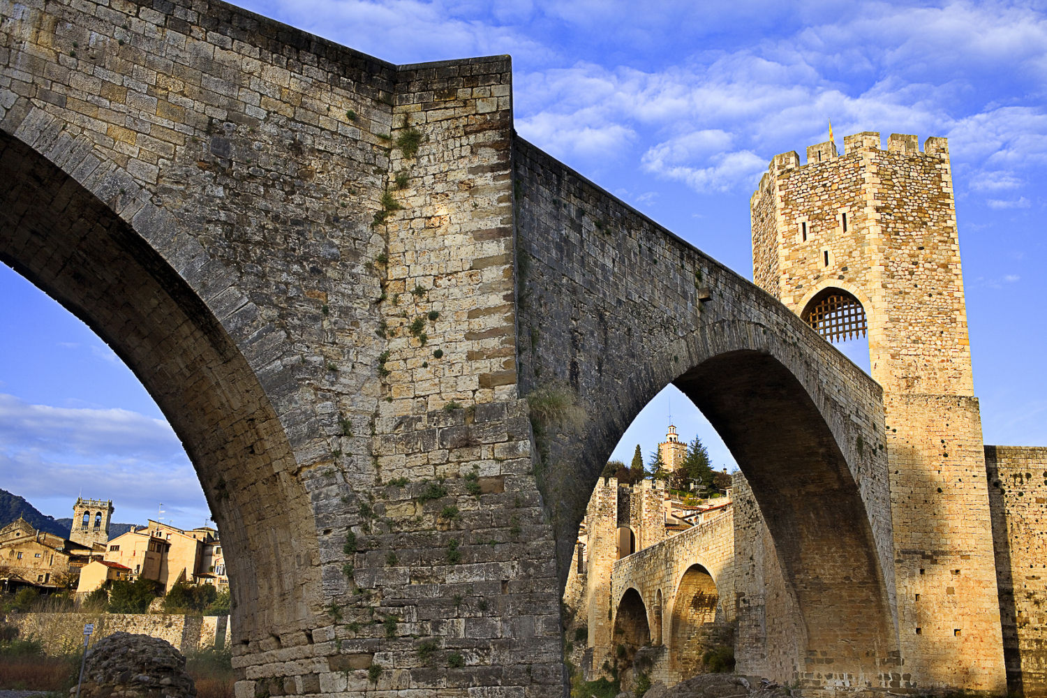Puente románico de Besalú. Es el acceso más monumental al pueblo, que alberga en su interior una arquitectura impactante, donde se encuentran obras como la antigua iglesia del monasterio de Sant Pere o la casa de Cornellà