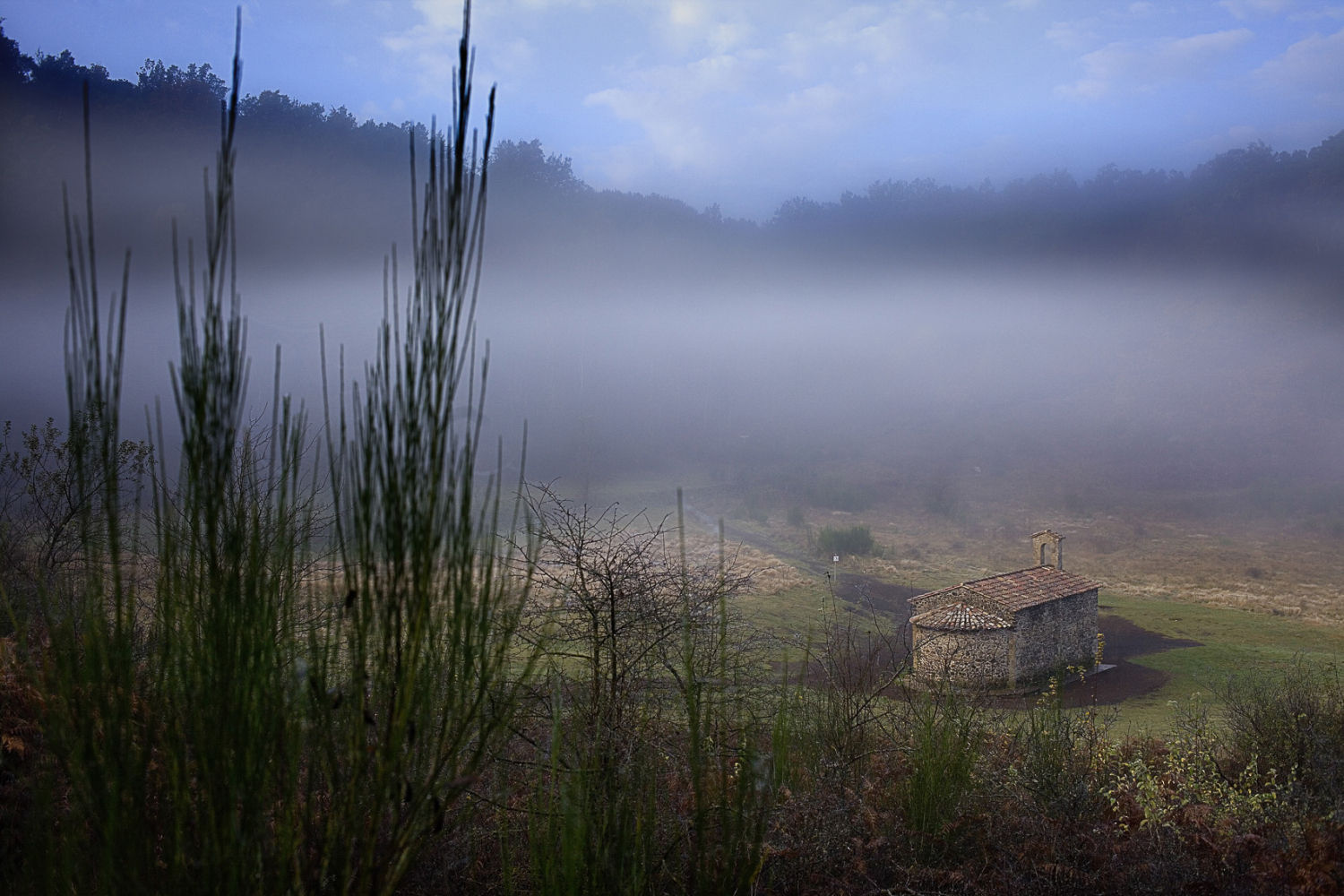 Cráter del volcán de Santa Margarida, con la ermita que le da nombre envuelta por la niebla. El paseo desde el parking hasta la ermita es corto pero muy agradable