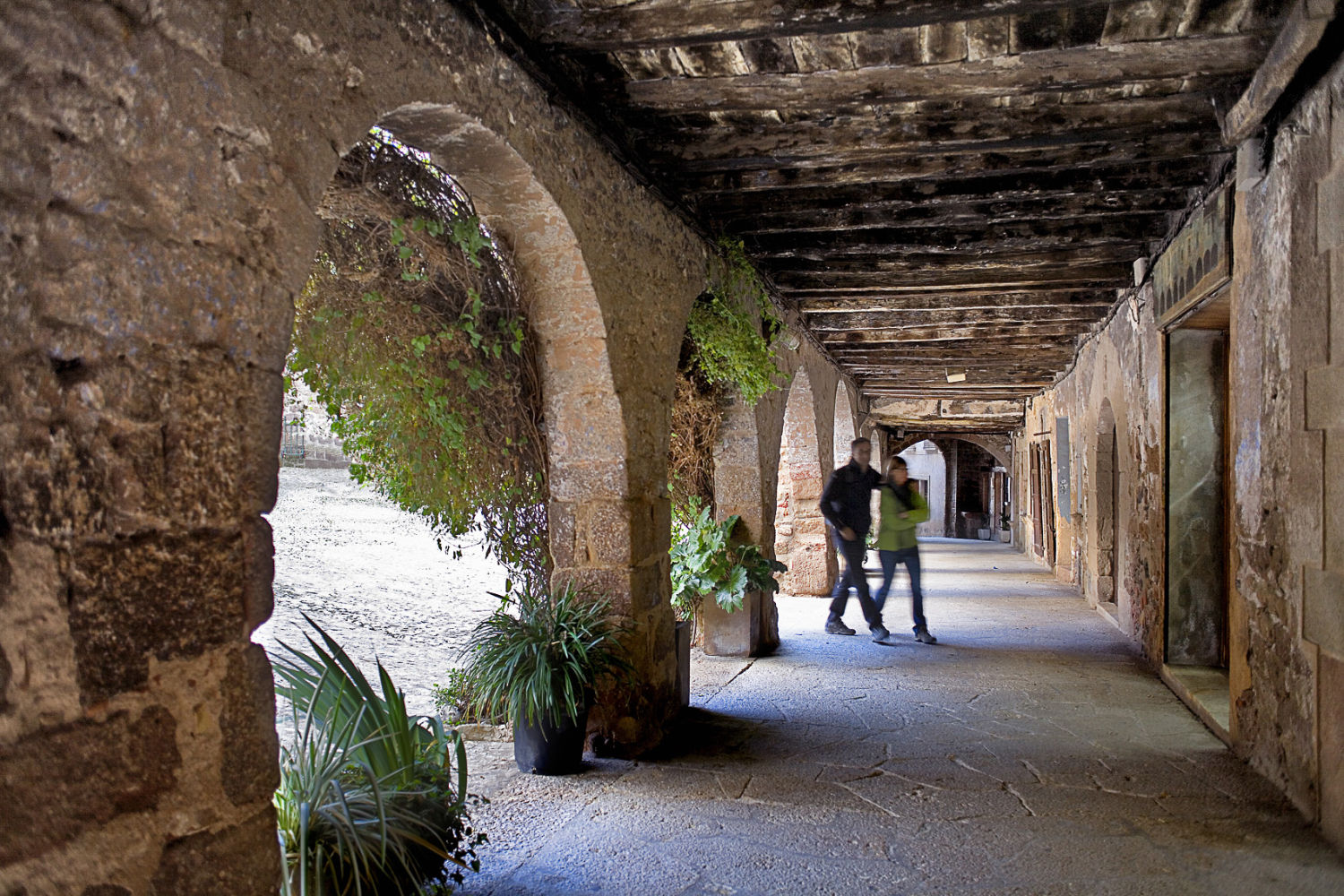 Zona porticada de la majestuosa plaza Mayor de la villa de Santa Pau, que se dispone en torno al castillo, de perfiles y arcadas irregulares que la hacen única y la dotan de una gran personalidad
