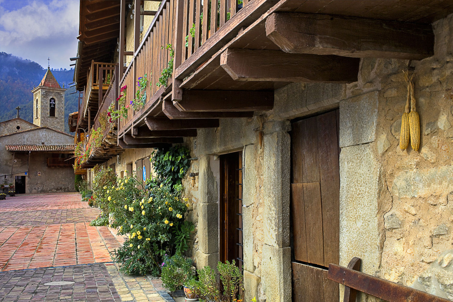 Els Hostalets d’en Bas es uno de los pueblos más fotogénicos de la comarca. De las paredes de las casas cuelgan panochas deshidratadas, y en verano o primavera sus balcones están llenos de flores