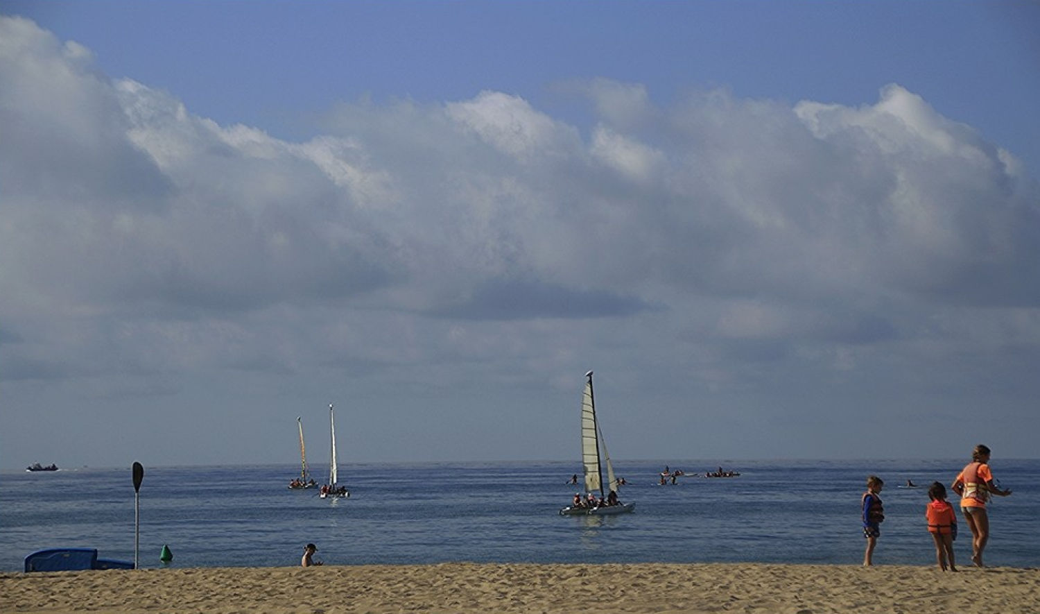 Poco bañistas y barcos a vela en la playa de Castelldefels a primera hora de la mañana.