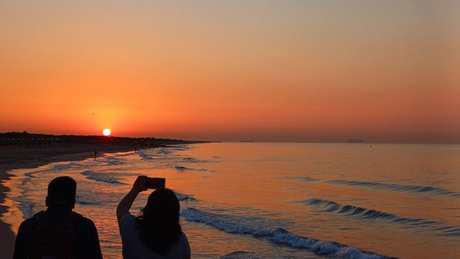 Radiante amanecer en la playa de Gavà, captando el momento mágico de una pareja fotografiando la salida del sol.