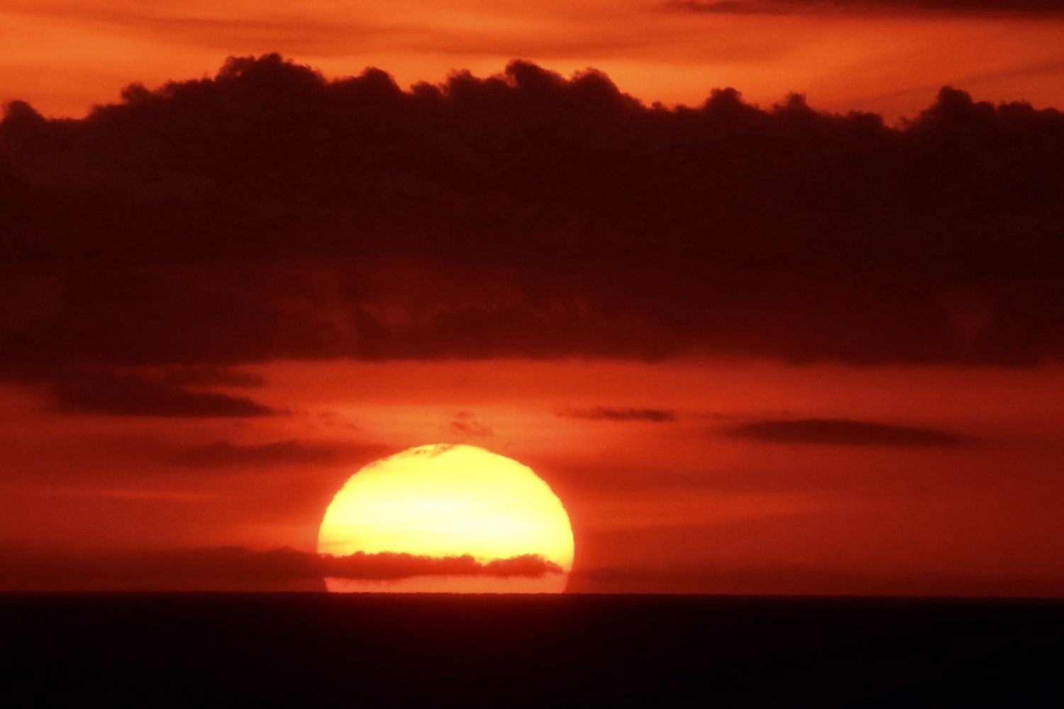 Sol naciente entre nubes visto desde el Far de Sant Sebastià.