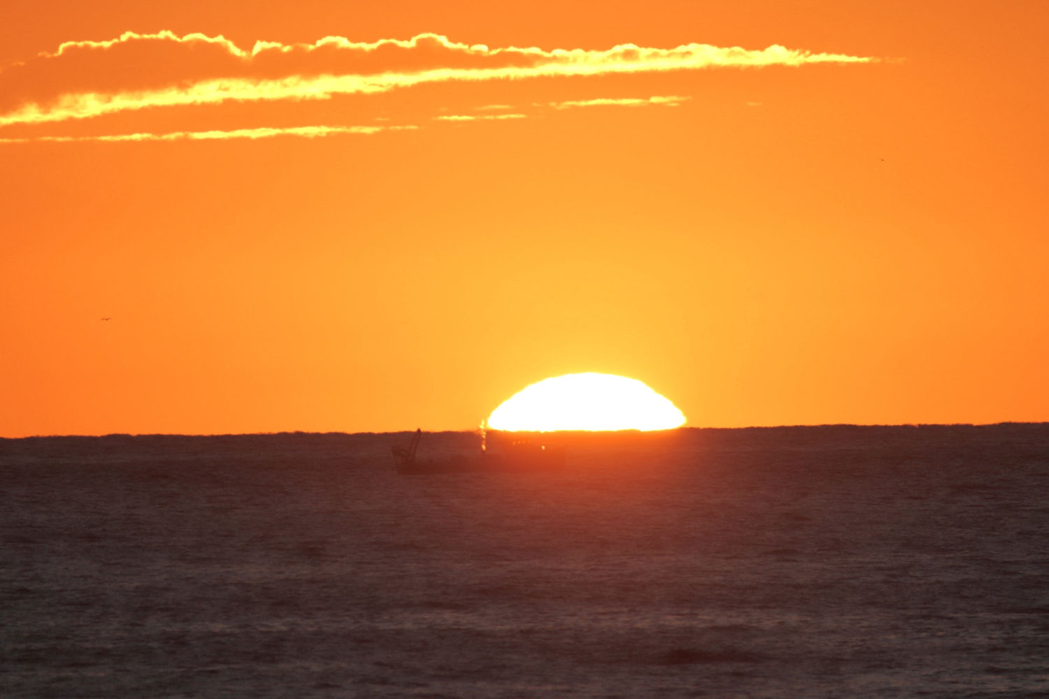 Sale en sol por el horizonte en la playa de Calella de Palafrugell.