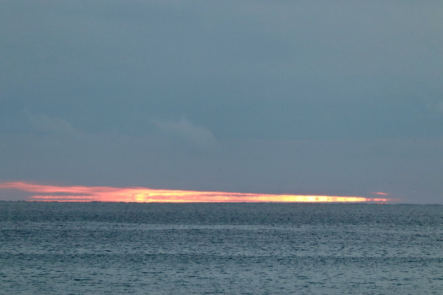 La línea del sol separa mar y cielo en La Fosca de Palamós.