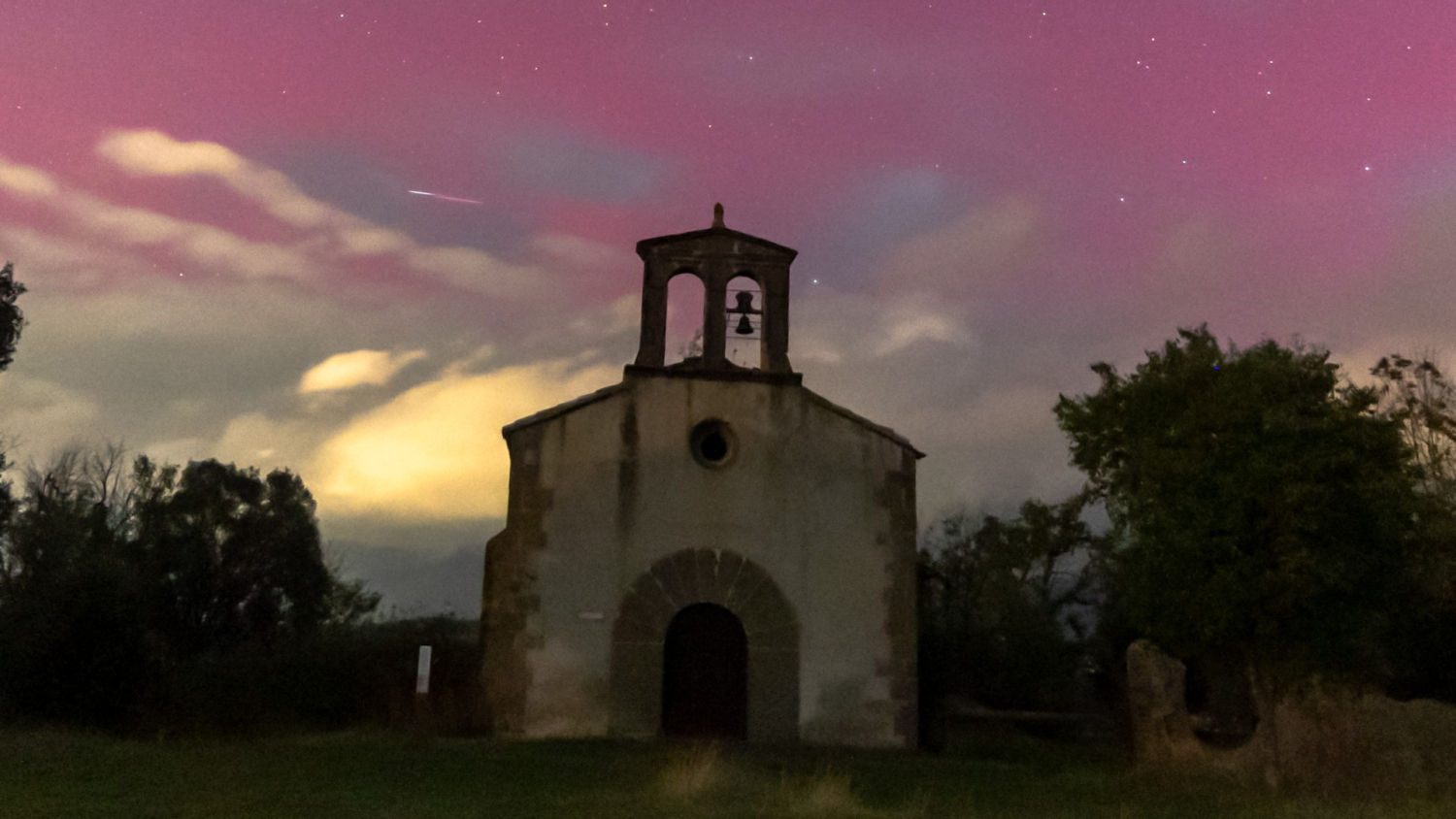 Noche de auroras en el cielo sobre la iglesia de Santa Maria de les Escales.