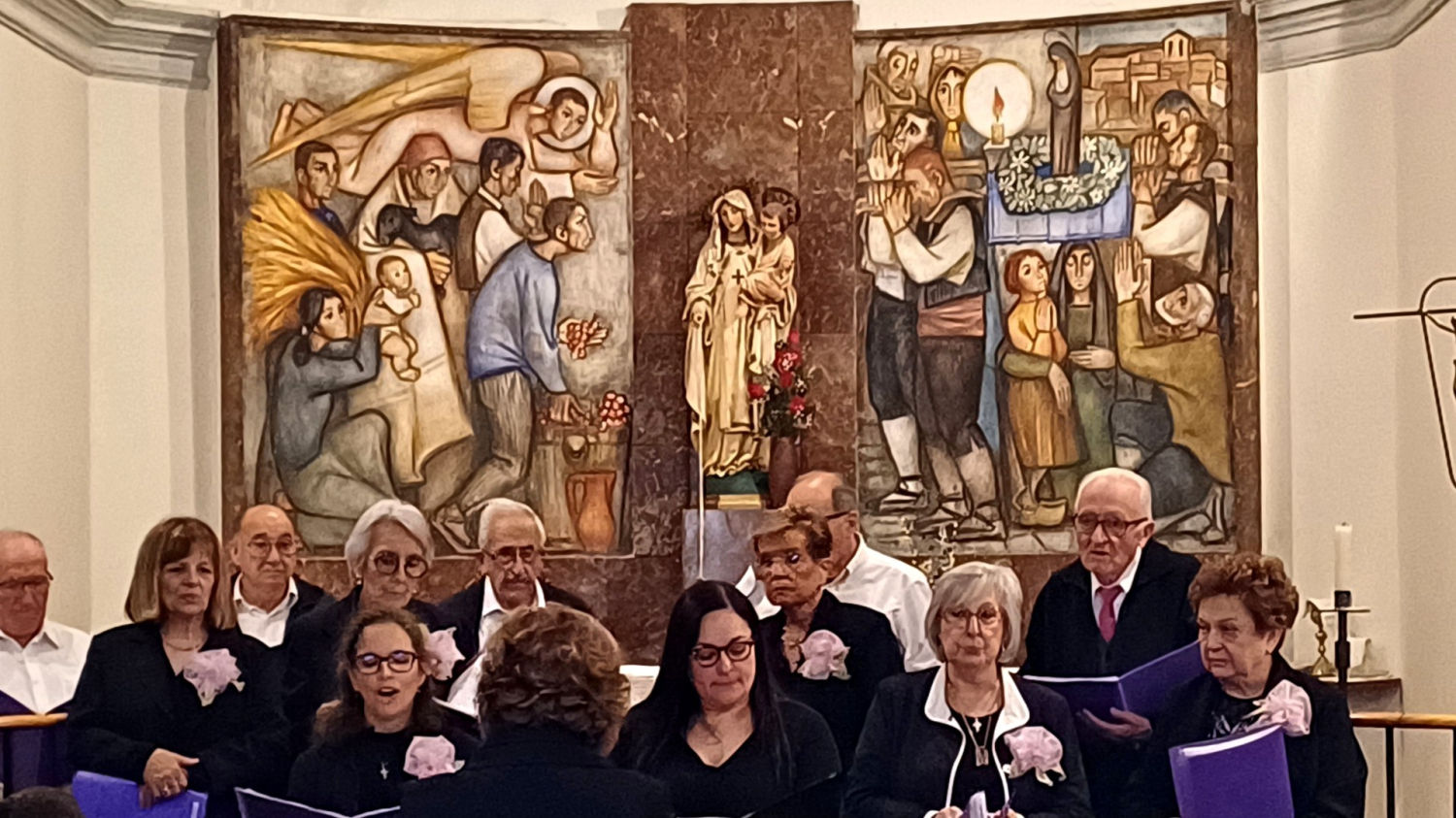 Una coral cantando delante del mural de Llucià Navarro i Rodón en la iglesia de Ossó de Sió.