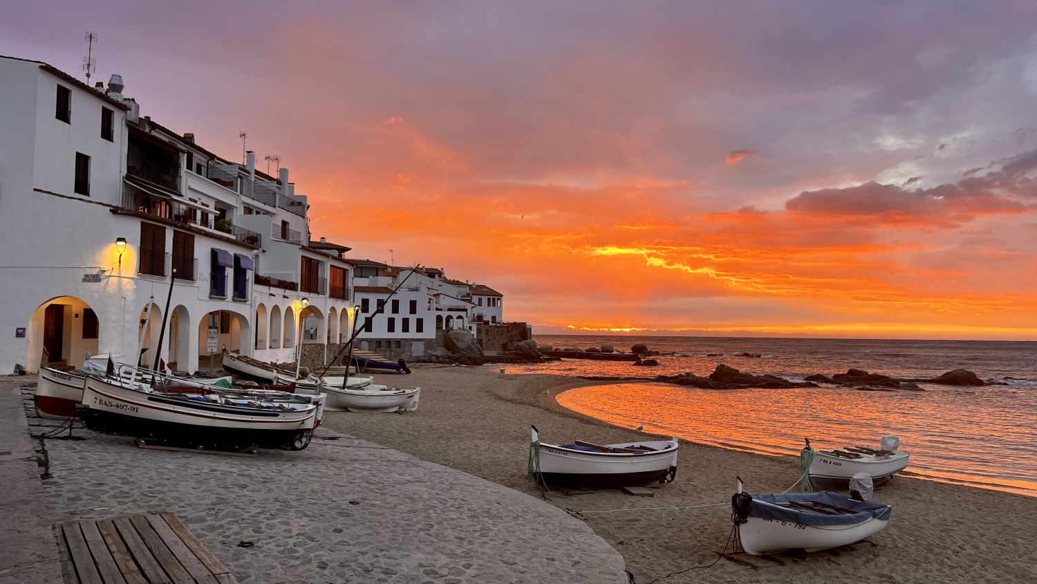 Barcas reposando en la orilla en el amanecer rojo de Calella de Palafrugell.