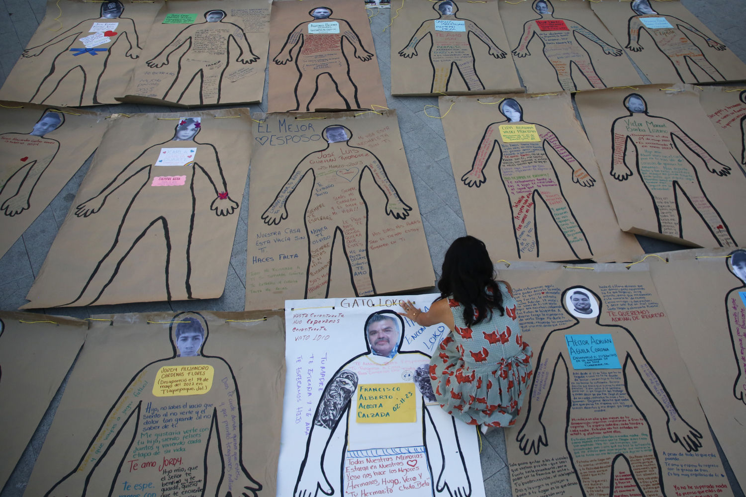 Una integrante del colectivo de familias de personas desaparecidas 'Luz de Esperanza' coloca carteles, durante una manifestación a las afueras de la Expo Guadalajara, este viernes en el marco 38 edición de la Feria Internacional del Libro de Guadalajara (FIL), Jalisco (México).