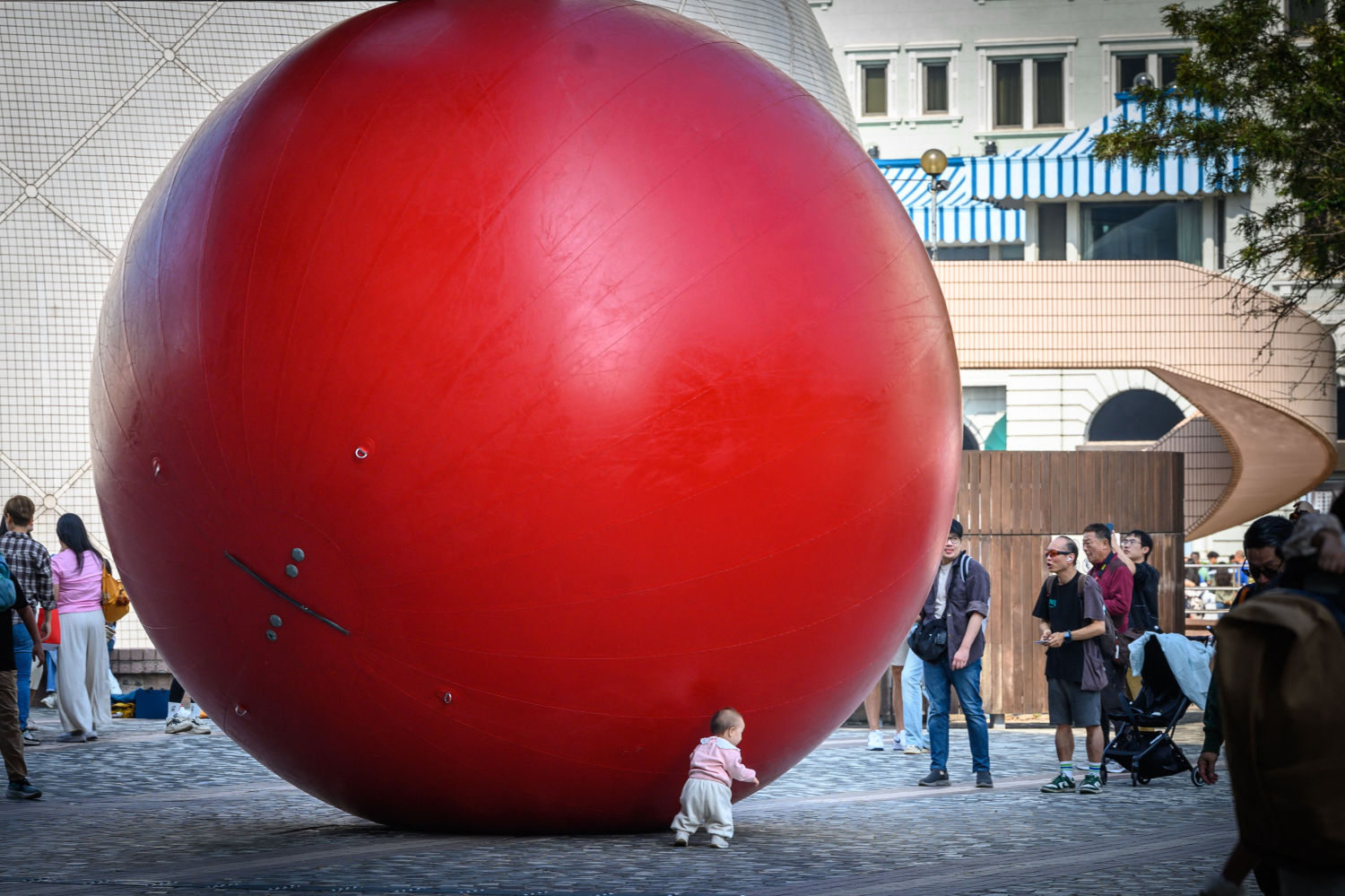 Un niño juega con una pelota roja inflable gigante en el Jardín de Salisbury en Hong Kong el 7 de diciembre de 2024.