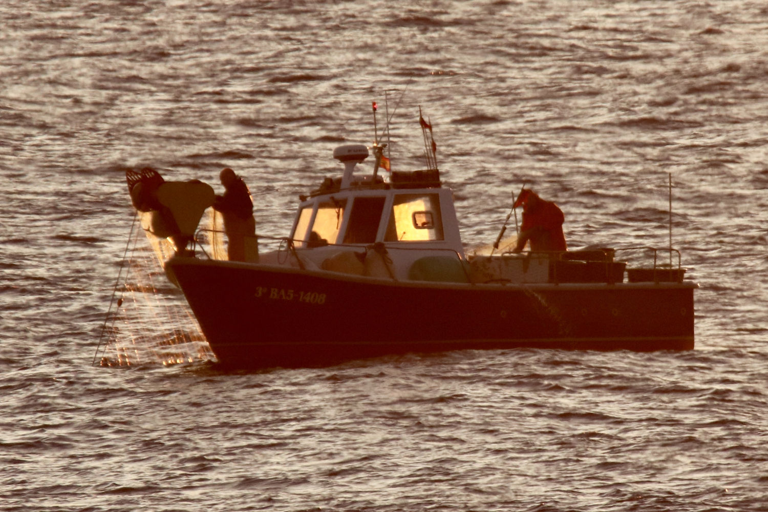 Barco de pescadores iluminados por los primeros rayos del sol.