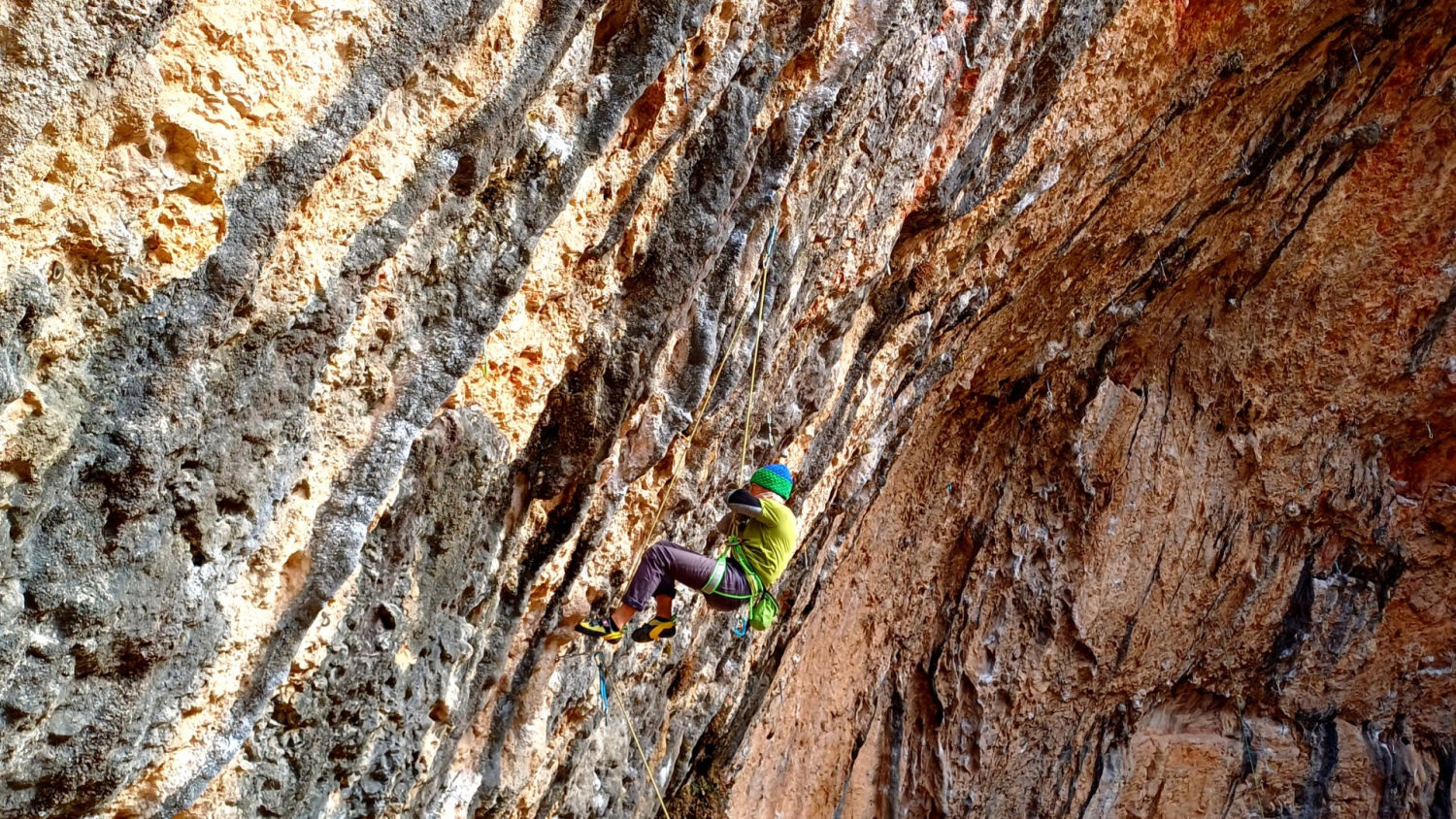 Escaladora subiendo la pared de la Cova Gran de Santa Linya.