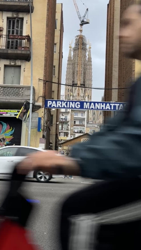 Otra perspectiva de la Sagrada Familia entre dos edificios al paso del motorista.