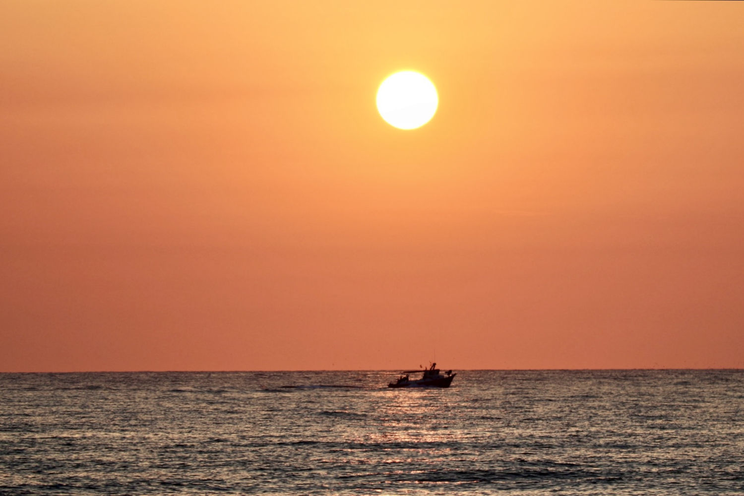 El sol luce al amanecer sobre el barco pesquero.