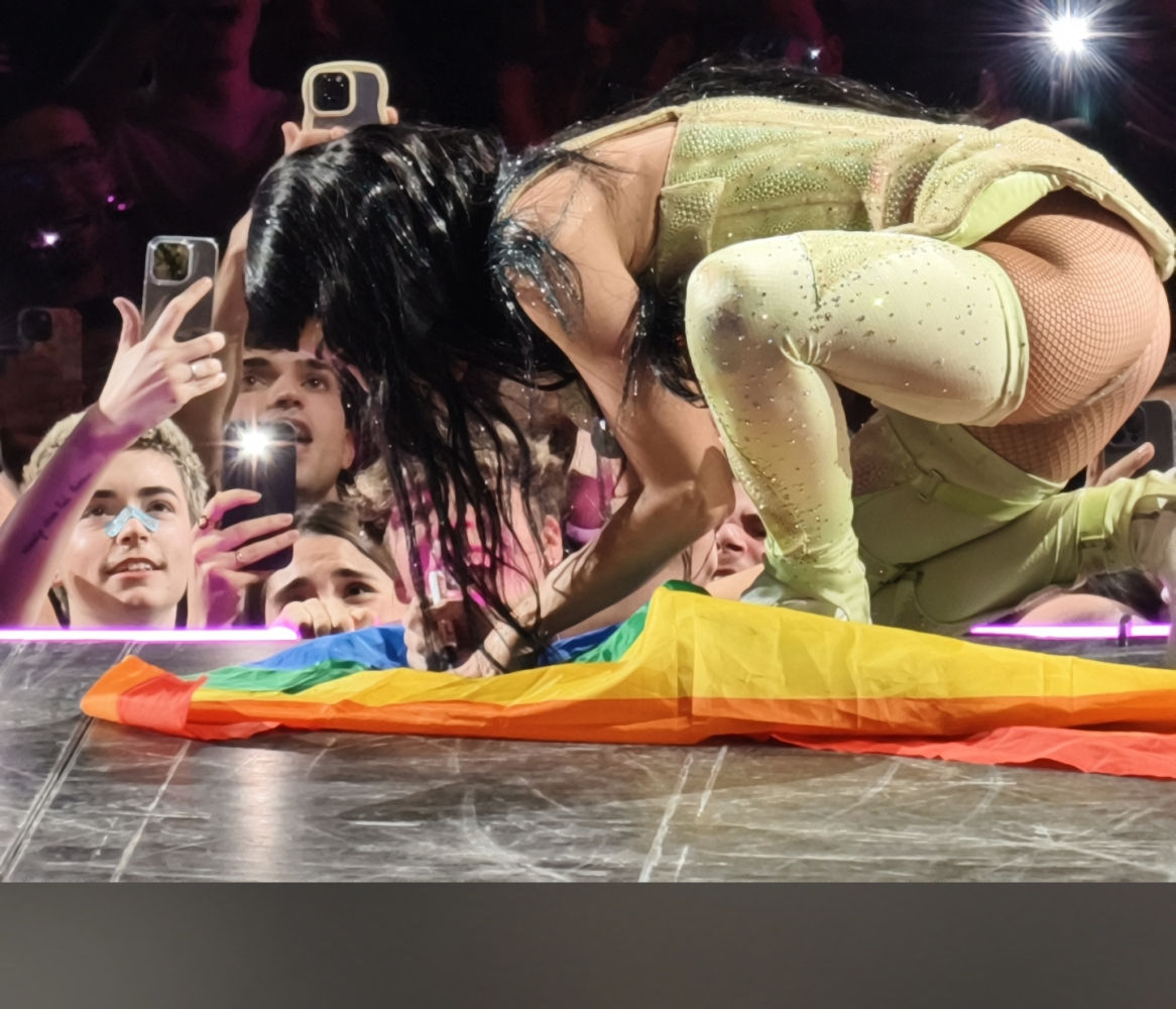 Katy Perry firma la bandera arcoíris de un espectador, durante el concierto.