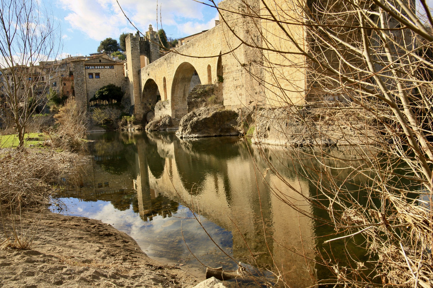 El puente de Besalú reflejado en el río.