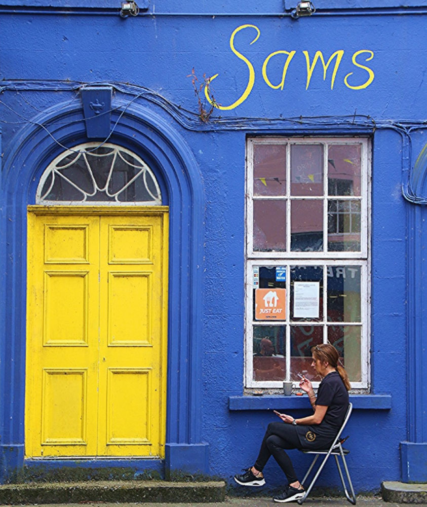 Fachada de un pub pintada de azul y amarillo.