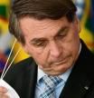Brazilian President Jair Bolsonaro takes off his face mask before speaking during the sanction of the law that authorizes states, municipalities and the private sector to buy vaccines against COVID-19, at the Planalto Palace in Brasilia, on March 10, 2021. - Until now, with more than 260,000 deaths by the coronavirus, only the federal Government was authorized to buy vaccines. (Photo by EVARISTO SA / AFP)