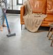 Happy woman with cordless vacuum easy cleaning floor at home in stylish interior design of living room. Smart home concept.