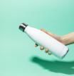 Close-up of female hand holding white reusable steel stainless thermo water bottle isolated on background of aqua menthe color. Plastic free.