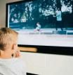 Rear view of boy watching smart TV in living room at home