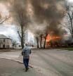 TOPSHOT - A man walks on a pavement as a house is burning following a shelling Severodonetsk, Donbass region, on April 6, 2022, as Ukraine tells residents in the country's east to evacuate 