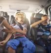 Los niños juguetones felices viajando en coche