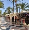 Turistas caminan ante los puestos de artesanía de La Explanada de España, en Alicante