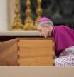Archbishop Georg Ganswein kneels by the coffin of late Pope Emeritus Benedict XVI after it's brought to St. Peter's Square for a funeral mass at the Vatican, Thursday, Jan. 5, 2023. Benedict died at 95 on Dec. 31 in the monastery on the Vatican grounds where he had spent nearly all of his decade in retirement. (AP Photo/Andrew Medichini)