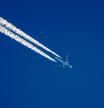 Distant passenger jet plane flying on high altitude on clear blue sky leaving white smoke trace of contrail behind. Air transportation concept�Un avión dejando una estela de condensación a su paso