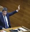 El presidente de la Generalitat, Carlos Mazón, vota a mano alzada en el Parlamento valenciano.